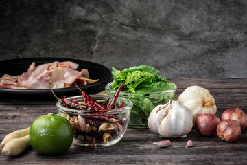  Spicy Thai food ingredients include bacon, red prick, garlic, lemongrass, basil, wood cutting and herbs on the old wood floor
