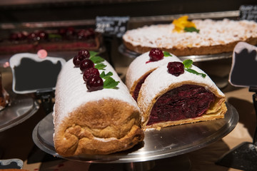 Delicious cherry strudel full of toppings covered with powdered sugar. Sweet dessert with fruit filling. The best bakery products in the city. Decorated with cherries and mint.