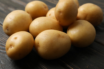 Young potato on wooden background, close up