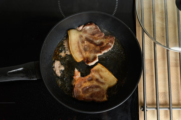 pork chop is cooked in a frying pan in sunflower oil