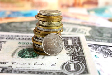  A stack of coins from different countries. One copper Russian ruble on a US dollar banknote