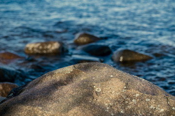 sunny beach with blue water and large rocks in the sand