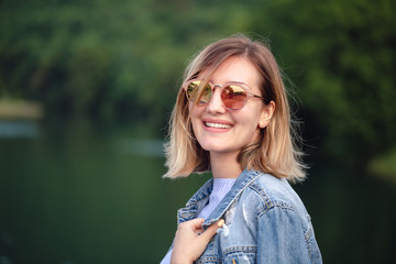 Beautiful young blond woman with retro red sunglasses. Outdoor photo