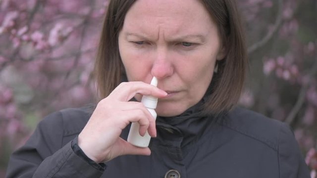 Woman using nasal spray outdoors