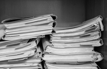 Paper documents stacked in archive. Documents on the shelves of archive room. Office shelves in the closet full of files. black and white photo