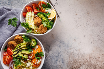 Buddha bowls salad with avocado, sweet potato, falafel, zucchini, tomatoes and broccoli, top view.