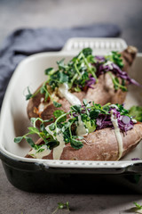 Baked sweet potatoes stuffed with quinoa, broccoli and cabbage, dark background.