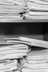 Paper documents stacked in archive. Documents on the shelves of archive room. Office shelves in the closet full of files. black and white photo