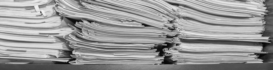 Paper documents stacked in archive. Documents on the shelves of archive room. Office shelves in the closet full of files. black and white photo