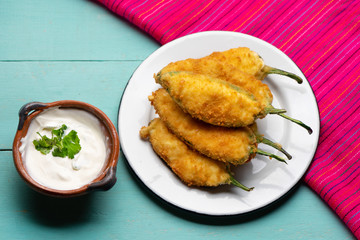 Mexican jalapeno poppers stuffed with cheese and breaded on turquoise background