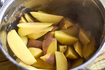 Freshly boiled potatoes in a pan on a wooden background.