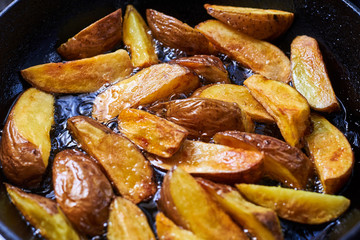 Fried crispy potatoes in oil in a pan. Cooking potatoes in a rustic way.