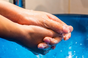 Naklejka premium A slow motion close-up shot of a young woman washing her hands with soap thoroughly