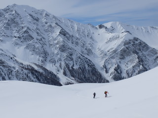 Naklejka premium Skieurs de ski de randonnée et alpiniste en montagne qui skient sur la neige et la glace en plein soleil des alpes dans le Queyras de saint Véran