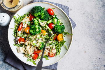 Vegan quinoa salad with tofu, broccoli, tomatoes and nutty dressing. Healthy food concept.
