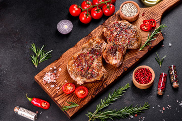 Fresh delicious juicy steak on the bones with vegetables and spices against a dark background