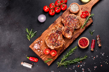 Fresh delicious juicy steak on the bones with vegetables and spices against a dark background