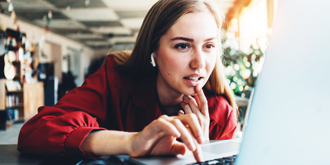 Interested woman works with laptop in bright spacious coworking