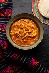 Mexican chicken tinga with chipotle sauce on dark background