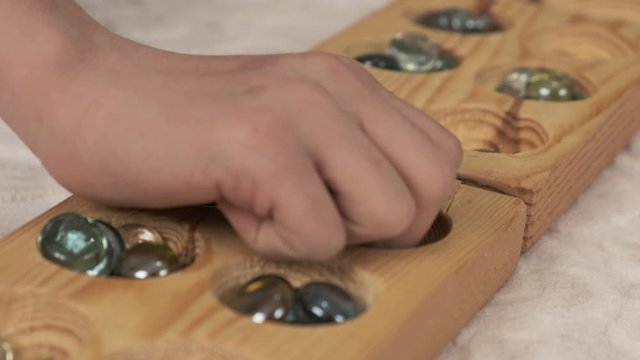a person playing mancala, playing mancala at home, mancala intelligence game on carpet,