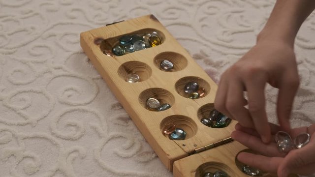 old intelligence games, wooden mancala game, a person playing mancala,