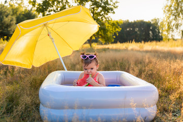 Little girl plays in the inflatable pool.