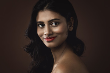 Fototapeta premium Indianka z pięknym makijażem i fryzurą na brązowym tle