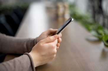 Woman sitting in cafe and chatting on modern cell phone