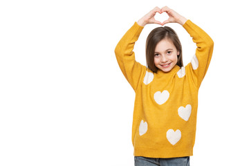 Studio portrait of a little girl on white background making a heart gesture with her hands. Fostering a child, humanitarian aid, cooperation, donation and support concept.