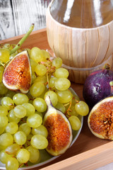 White grapes, figs and italian spirit Grappa on wooden tray. Still life