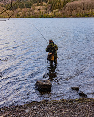 Fisherman wading in a lough with a bag and camouflage clothing