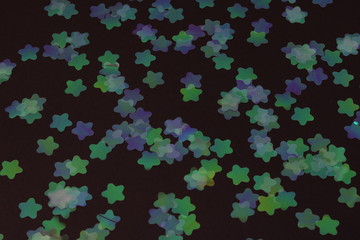 colored twinkling stars on a black background top view. star confetti