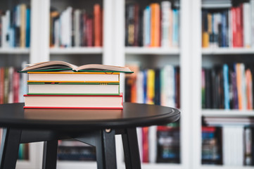 A stack of books on a black table. Library in the background. Stack of books close up.