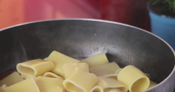 Pasta paccheri just drained and poured into a pan with tomatoes sauce.