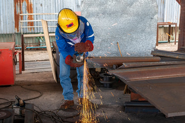 Worker is used Grinding Machine to grinding surface of H-Beam steel after cutting, at Industrial factory.