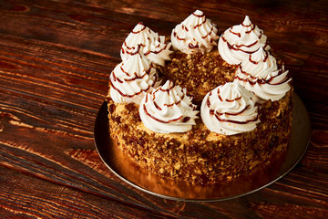 Roasting meringue cake with nuts and cream on wood background