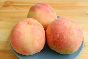 Fototapeta na wymiar Plate of Three Fresh Ripe Peaches on Wooden Table 
