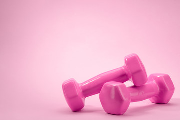 Dumbbells on pink background with copy space