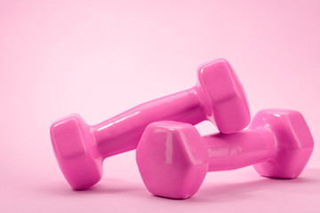 Close-up on a pair of dumbbells on pink background