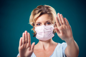 A portrait of woman with face medical mask showing stop gesture. People, healthcare and medicine concept