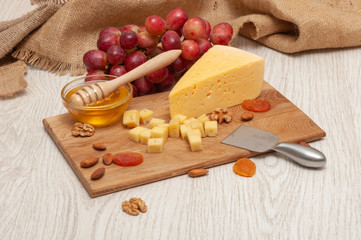 cheese on a board with honey, grapes, dried apricots and nuts