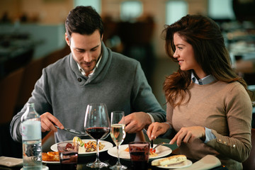 Happy loving couple enjoying in restaurant. Young couple enjoying in food.