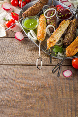Summer bbq party. Shish kebab on a stick, from ground beef and chicken meat. Lula kebab, traditional Caucasian asian dish. With various sauces, spices and tomatoes, grey stone background