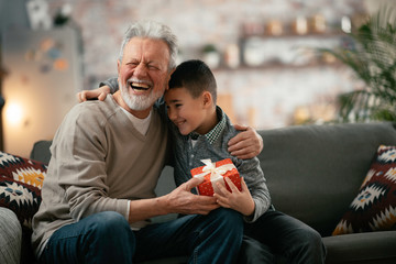 Grandfather giving gift to grandson.	