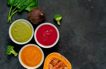 Set of vegetable soups. Broccoli, spinach, green peas soup. Pumpkin and carrot soup. Beetroot and carrot soup on a stone background  with copy space for your text