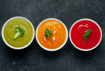 Set of vegetable soups. Broccoli, spinach, green peas soup. Pumpkin and carrot soup. Beetroot and carrot soup on a stone background  with copy space for your text