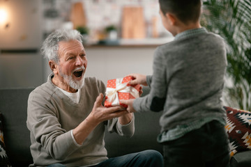 Grandfather giving gift to grandson.	