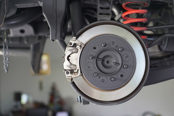 Disc brake of the vehicle for repair, in process of new tire replacement.  Car brake repairing in garage.Selective focus disc brake on car, in process of new tire replacement.Close up.