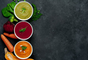 Set of vegetable soups. Broccoli, spinach, green peas soup. Pumpkin and carrot soup. Beetroot and carrot soup on a stone background  with copy space for your text