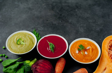 Obraz na płótnie Canvas Set of vegetable soups. Broccoli, spinach, green peas soup. Pumpkin and carrot soup. Beetroot and carrot soup on a stone background with copy space for your text